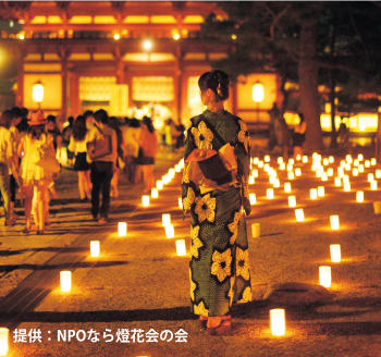 無数のろうそくの灯りの中に立つ浴衣の女性