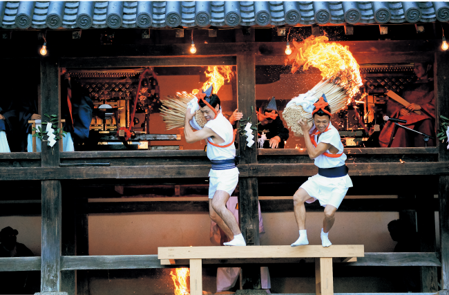 燃えさかる火松明を担ぐ